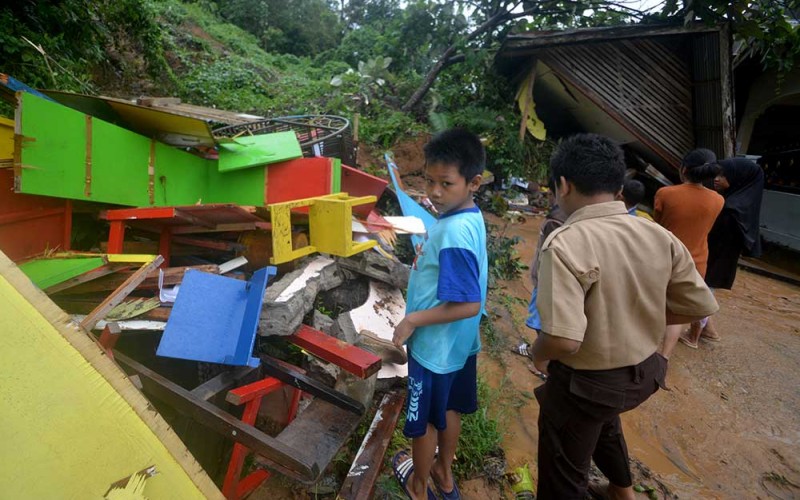 Sejumlah anak berada di depan bangunan yang hancur karena longsor di Batubusuk, Padang, Sumatera Barat, Kamis (22/9/2022). Badan Penanggulangan Bencana Daerah (BPBD) Padang menyebutkan intensitas hujan tinggi pada Rabu (21/9/2022) menyebabkan longsor dan pohon tumbang yang menimpa bangunan sekolah PAUD serta menghambat akses jalan pedesaan. ANTARA FOTO/Iggoy el Fitra