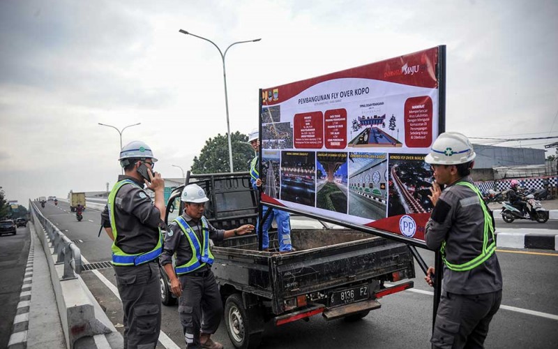 Pekerja membawa papan progres pembangunan Jalan Layang Kopo di Bandung, Jawa Barat, Kamis (22/9/2022). Kementerian PUPR melakukan uji laik fungsi Jalan Layang Kopo pada Rabu (21/9/2022) pukul 00.00 guna memastikan kelaikan dan keamanan konstruksi jalan layang sebelum di resmikan. ANTARA FOTO/Raisan Al Farisi