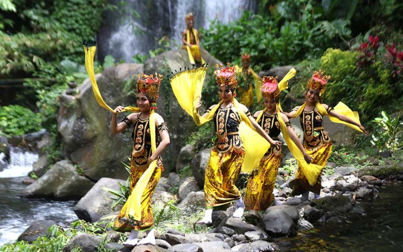 Penari Gandrung menari dengan latar belakang air terjun Jagir di Banyuwangi, Jawa Timur, Kamis (22/09/2022).  Sejumlah seniman tari bersama pengelola wisata mengkolaborasikan unsur seni daerah setempat sebagai pariwisata yang berbasis budaya (Cultural Tourism) untuk menambah daya tarik dan meningkatkan kunjungan wisata. ANTARA FOTO/Budi Candra Setya