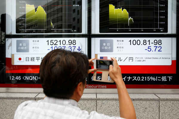 Seorang pejalan kaki memotret display indeks di Jepang. Reuters - Thomas Peter