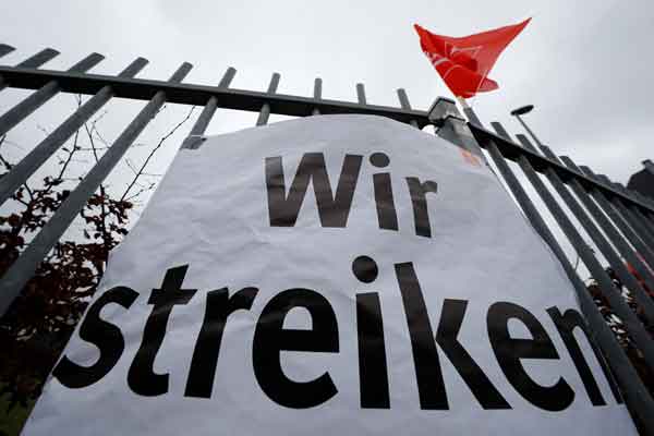 Sebuah plakat bertuliskan "Wir Streiken" terpampang di pintu masuk sebuah pabrik di Jerman.  - Reuters