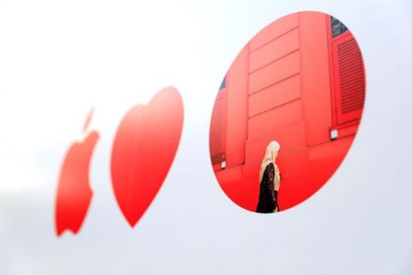 Logo Apple berada di sebelah lambang hati dan titik merah menggambarkan karya seniman lokal di fasad toko Apple Singapura pertama, Jumat (5/5/2017). - Reuters