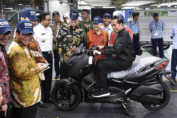 Presiden Joko Widodo (tengah) menjajal motor Yamaha XMax di pabrik PT Yamaha Indonesia Motor Manufacturing, Jakarta, Senin (3/12/2018). Presiden menyempatkan waktu untuk makan siang bersama karyawan dan melepas pencapaian ekspor 1,5 juta unit sepeda motor Yamaha. - ANTARA/Puspa Perwitasari 