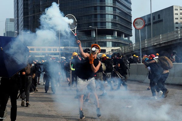 Para pemrotes RUU Anti-ekstradisi menggunakan raket tenis untuk memukul tabung gas air mata saat pawai menuntut demokrasi dan reformasi politik di Teluk Kowloon, Hong Kong, pada Sabtu (24/8/2019). - Reuters/Tyrone Siu