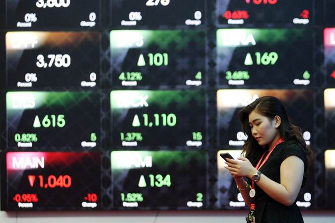Pengunjung menggunakan ponsel di dekat papan elektronik yang menampilkan perdagangan harga saham di BEI, Jakarta, Selasa (11/6/2019). - Bisnis/Dedi Gunawan