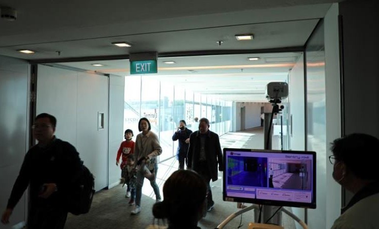 Petugas bandara memantau pemindai termal saat penumpang lewat setelah kedatangan penerbangan dari Hangzhou, China di Bandara Changi, Singapura, 22 Januari 2020. -  REUTERS / Yiming Woo