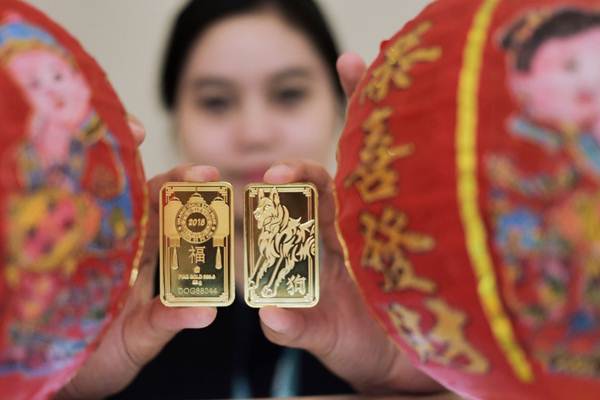 Karyawati memperlihatkan emas batangan 88 gram bergambar Shio Anjing Tanah milik PT Aneka Tambang Tbk (Antam), di Jakarta, Kamis (18/1). - JIBI/Felix Jody Kinarwan