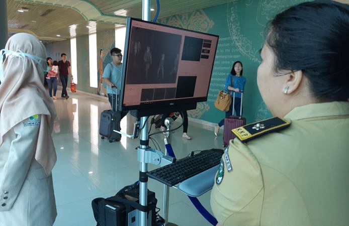 Petugas Kantor Pelabuhan Palembang memeriksa suhu tubuh penumpang di Bandara SMB II Palembang menggunakan thermal scanner. - Bisnis / Dinda Wulandari