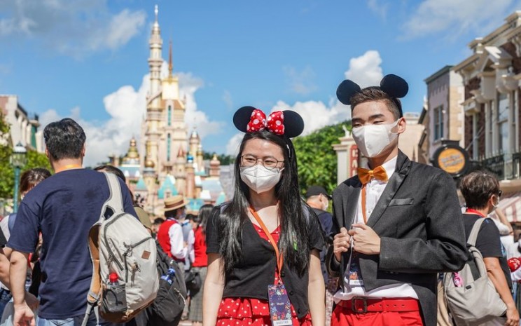 Pelancong berfoto mengunakan masker di Disneyland Hong Kong -  Bloomberg