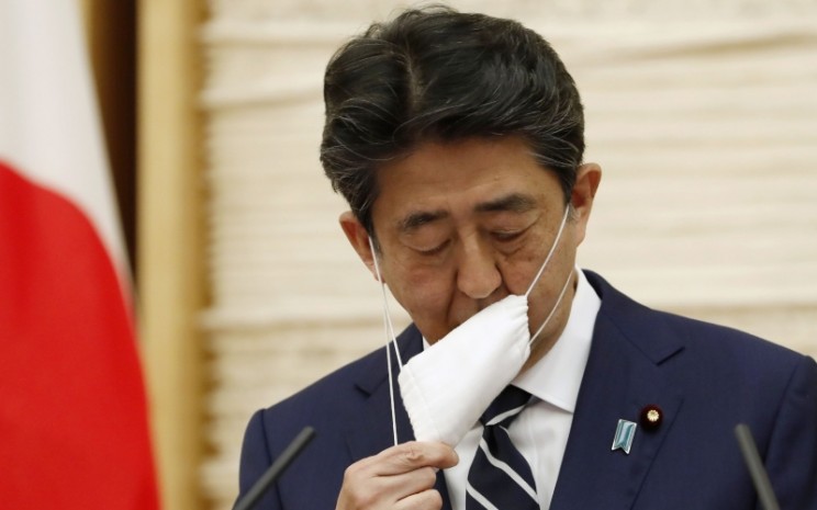 Perdana Menteri (PM) Jepang Shinzo Abe melepas maskernya sebelum berbicara dalam sebuah konferensi pers di Tokyo, Jepang, Senin (25/5/2020)./Bloomberg - Reuters/Kim Kyung/Hoon