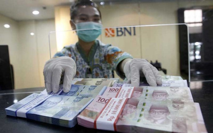 Karyawati menunjukan Uang Rupiah dan Dollar AS di salah satu kantor cabang Bank BNI di Jakarta, Kamis (3/9/2020).  Bisnis - Himawan L Nugraha