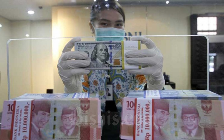 Karyawati menunjukan Uang Rupiah dan Dollar AS di salah satu kantor cabang Bank BNI di Jakarta, Kamis (3/9/2020).  Bisnis - Himawan L Nugraha