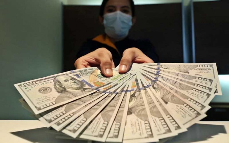 Karyawan menunjukan dolar AS di Jakarta, Rabu (11/11/2020). Nilai tukar Rupiah terhadap dolar AS pada perdagangan Rabu (11/11) ditutup melemah 0,2 persen atau 27,5 poin ke level Rp14.085 per dolar AS. Bisnis - Eusebio Chrysnamurti