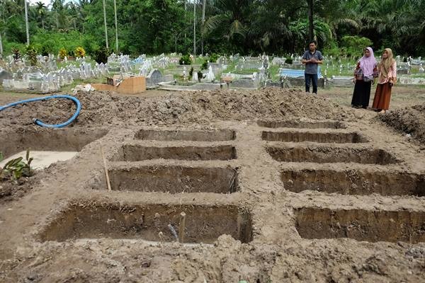Warga melihat liang kubur yang telah disiapkan untuk pemakaman korban kebakaran pabrik korek api gas (mancis) di perkuburan muslim, Desa Sambirejo, Langkat, Sumatera Utara, Minggu (23/6/2019).  - Antara