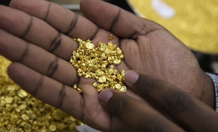 Seorang karyawan memegang beberapa butiran emas di Perth Mint Refiner. -  Carla Gottgens / Bloomberg