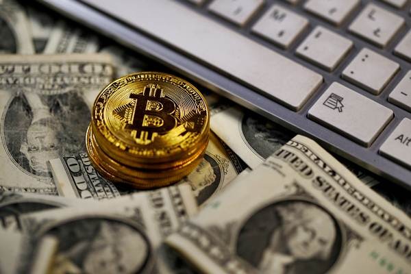 Ilustrasi Bitcoin diletakkan di atas lembaran uang dolar AS. - REUTERS/Dado Ruvic