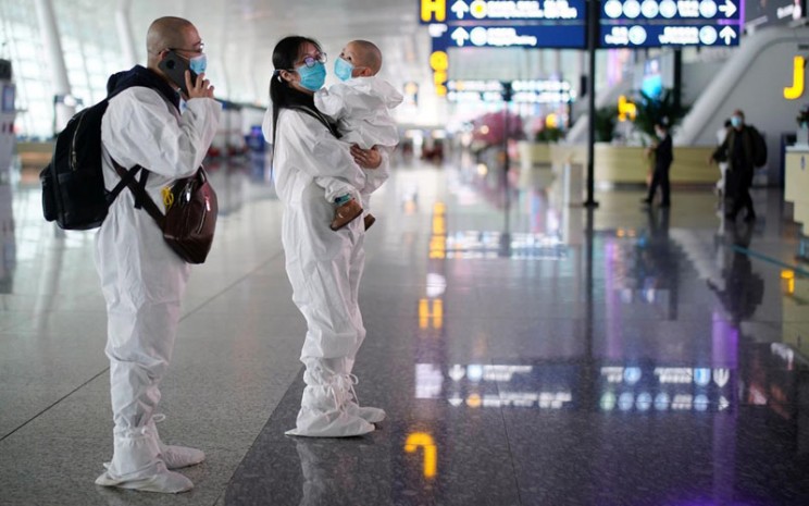 Sepasang orang tua beserta bayinya menggunakan pakaian pelindung saat berada di Bandara Internasional Tianhe Wuhan, ibu kota Provinsi Hubei, China, yang menjadi pusat wabah virus corona jenis baru COVID-19 pada Jumat (10/4/2020)./Antara - Reuters