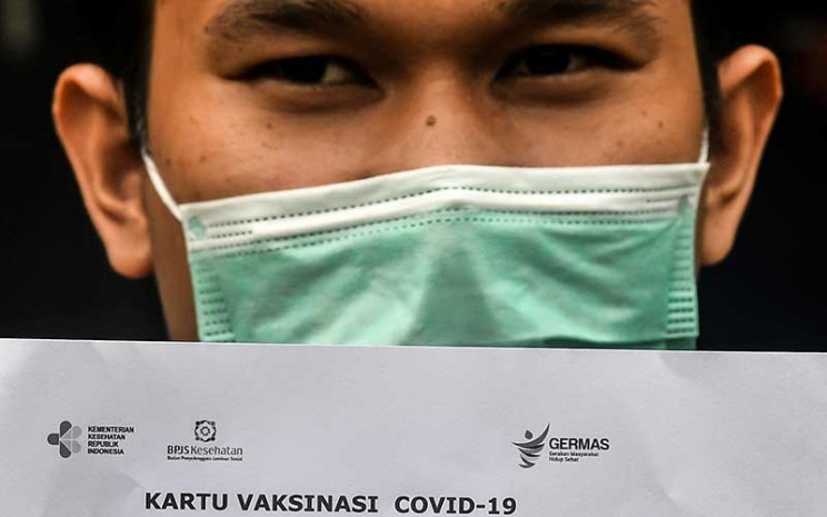 Seorang pasien menunjukkan kartu vaksinasi Covid-19 saat simulasi pemberian vaksin Covid-19 Sinovac di Puskesmas Kelurahan Cilincing I, Jakarta, Selasa (12/1/2021). ANTARA FOTO - Muhammad Adimaja