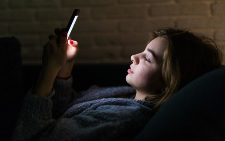 Ilustrasi perempuan memainkan gadget karena insomnia - Freepik.com