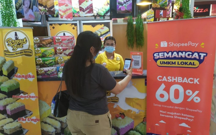 Keterangan foto: Tampak seorang pengunjung sedang melakukan transaksi menggunakan ShopeePay sembari menikmati promo Cashback 60% di sentra kuliner Tiara Dewata