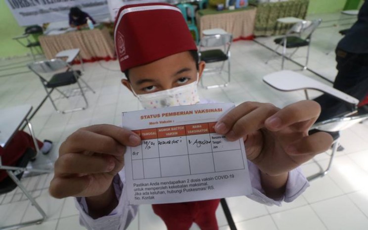 Seorang anak memperlihatkan kartu vaksinasi usai mendapatkan suntikan vaksin COVID-19 di Madrasah Ibtidaiyah Negeri 2 Kediri, Jawa Timur, Selasa (14/12/2021). Pemerintah akan menggunakan 6,4 juta dosis vaksin Sinovac untuk anak hingga akhir Desember 2021. ANTARA FOTO/Prasetia Fauzani - 