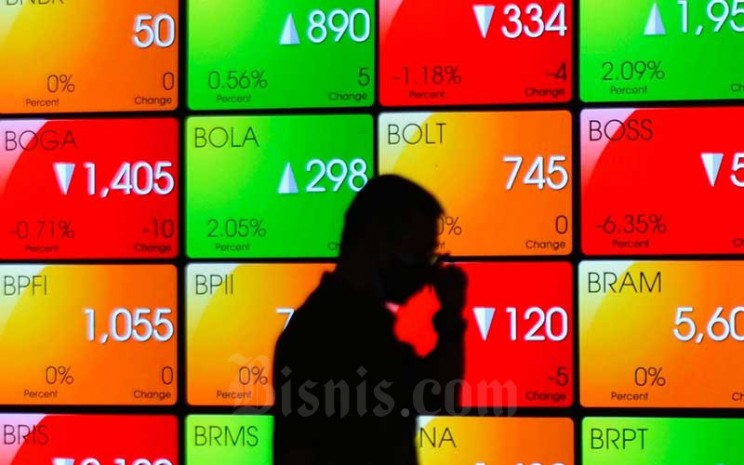 Karyawan melintas di dekat layar pergerakan indeks harga saham gabungan (IHSG) di Bursa Efek Indonesia, Jakarta, Selasa (29/6/2021). Bisnis - Fanny Kusumawardhani