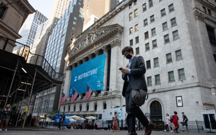 Seorang pejalan kaki yang memakai masker lewat di depan gedung bursa saham New York Stock Exchange (NYSE), New York, AS, pada Kamis, (22/7/2021). - Bloomberg
