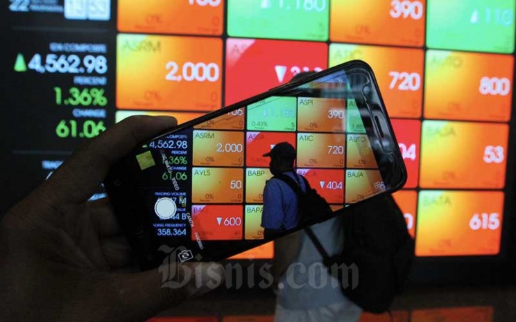 Pengunjung menggunakan smarphone didekat papan elektronik yang menampilkan perdagangan harga saham di Jakarta, Rabu (22/4/2020). Bisnis - Dedi Gunawan