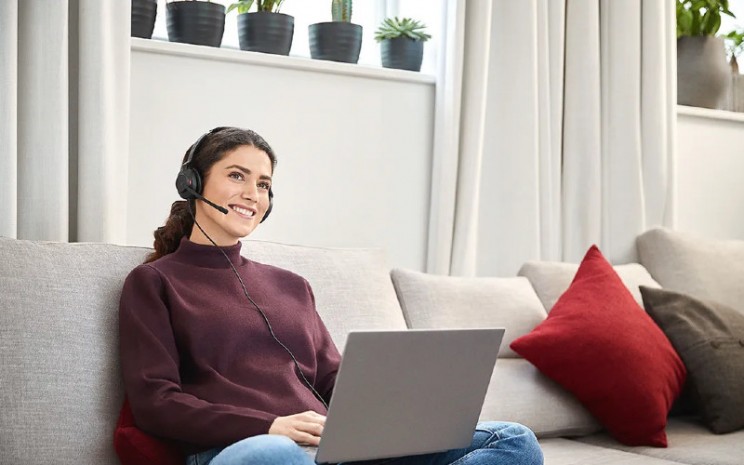 Seorang perempuan sedang bekerja di rumah sambil mendengar musik MP3 yang didownload - apac.jabra.com