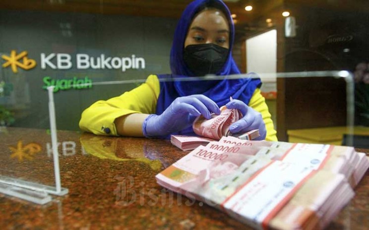 Karyawati menghitung uang rupiah di kantor cabang Bank KB Bukopin Syariah di Jakarta, Selasa (21/12/2021). Bisnis - Himawan L Nugraha