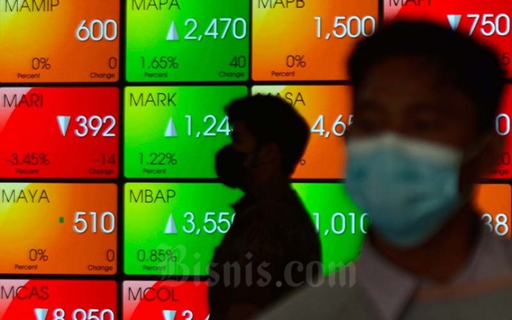 Karyawan melintas di dekat layar pergerakan indeks harga saham gabungan (IHSG) di Bursa Efek Indonesia (BEI) Jakarta, Rabu (19/1/2022). Bisnis - Fanny Kusumawardhani