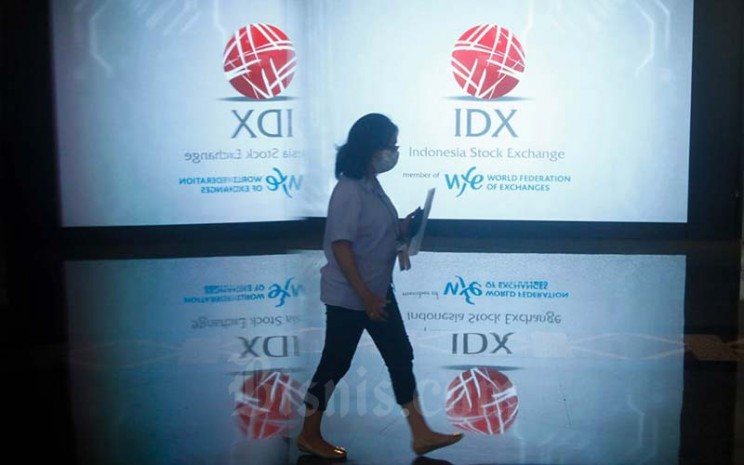 Pegawai melintas di dekat layar yang menampilkan logo Bursa Efek Indonesia (BEI) di Jakarta, Senin (24/1/2022). Bisnis - Himawan L Nugraha