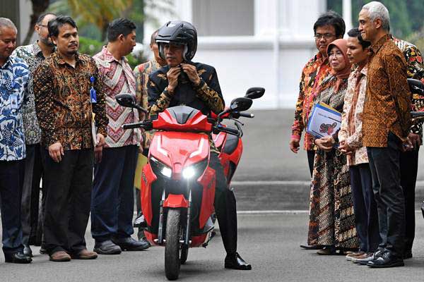 Presiden Joko Widodo mengenakan helm sebelum menjajal motor listrik buatan dalam negeri 'Gesits' seusai melakukan audiensi dengan pihak-pihak yang terkait produksi di halaman tengah Istana Kepresidenan, Jakarta, Rabu (7/11/2018). - ANTARA/Wahyu Putro A