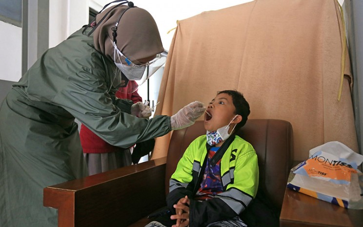 Petugas melakukan tes PCR kepada penumpang anak-anak sebelum melakukan perjalanan kereta api di Stasiun Jatibarang, Indramayu, Jawa Barat, Sabtu (25/12/2021).  - Antara Foto/Dedhez Anggara/YU\\r\\n