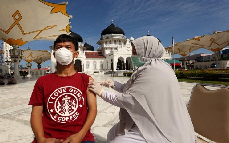 Warga mendapatkan suntikan vaksin Covid-19 oleh petugas kesehatan (kanan) pada vaksinasi merdeka di halaman masjid raya Baiturrahman, Banda Aceh, Aceh, Senin (6/9/2021). Vaksinasi merdeka yang digelar secara serentak pada 6-7 September 2021 di seluruh Indonesia merupakan program sinergi staf khusus Presiden bersama Kapolri dan Panglima TNI untuk membantu pemerintah memutuskan mata rantai penyebaran serta penularan Covid-19. ANTARA FOTO  -  Irwansyah Putra