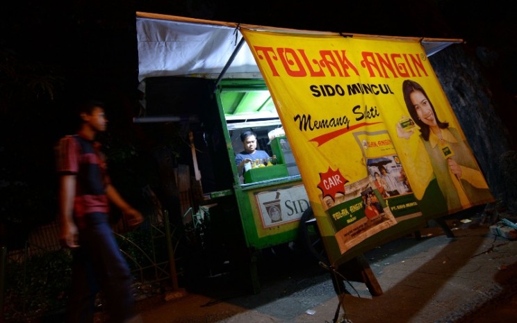 Sebuah iklan Tolak Angin produksi PT Industri Jamu Dan Farmasi Sido Muncul Tbk. (SIDO) terpampang di sebuah warung pinggir jalan di Jakarta, Minggu (16/2/2014). Bloomberg - Dimas Ardian