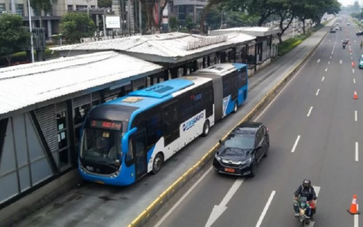 Bus TransJakarta berhenti di Halte Gelora Bung Karno untuk menaikkan dan menurunkan penumpang di Jakarta, Minggu (30/1/2022). - Antara