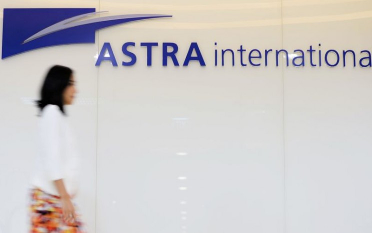 Karyawan melintas di depan logo PT Astra International Tbk. - Bloomberg / Dimas Ardian