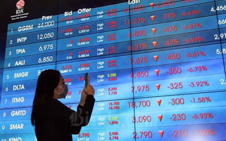 Pengunjung berada didekat papan elektronik yang menampilkan perdagangan harga saham di lantai Bursa Efek Indonesia di Jakarta, Jumat (13/3/2020). Bisnis - Dedi Gunawan