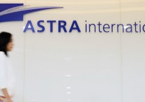 Seorang wanita berjalan melewati papan nama PT Astra International Tbk. (ASII), di Jakarta, Rabu (4/6/2014). Bloomberg - Dimas Ardian