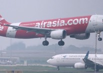 Pesawat milik PT AirAsia Indonesia Tbk. (CMPP) bersiap mendarat melewati pesawat PT Garuda Indonesia Tbk. (GIAA) di Bandara Internasional Soekarno-Hatta di Cengkareng, Senin, (24/5/2021). Bloomberg - Dimas Ardian