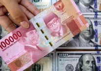 Petugas menunjukkan uang rupiah dan dolar AS di salah satu gerai penukaran mata uang asing di Jakarta, Senin (16/3/2020)./Bisnis-Arief Hermawan P 