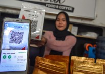 Seorang warga menggunakan pembayaran nontunai Quick Response Indonesia Standard (QRIS) saat membeli kopi di warung kopi Jalik Rumbuk di Mataram, NTB, Selasa (12/1/2021)./ANTARA FOTO-Ahmad Subaidi. Intip Persaingan ARTO, BBSI, BBYB, BANK, dkk di Segmen UMKM